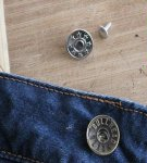 Instructions on how to properly repair or replace a button on jeans