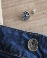 Instructions on how to properly repair or replace a button on jeans