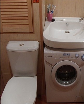 The washing machine is located next to a sink or under a heated towel rail.