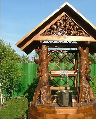 A wooden well looks beautiful surrounded by flowers and low bushes.