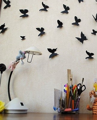 On a curtain fabric, a soft shade, vinyl wallpaper of moths is fixed with pins.