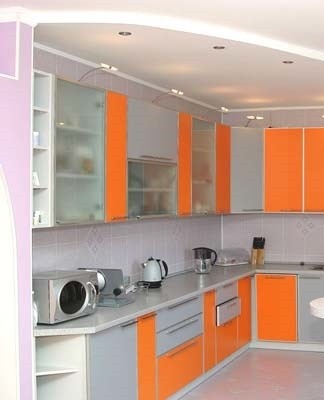 The gray-orange kitchen looks modern.