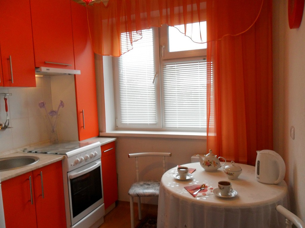 The gray-orange kitchen looks modern.