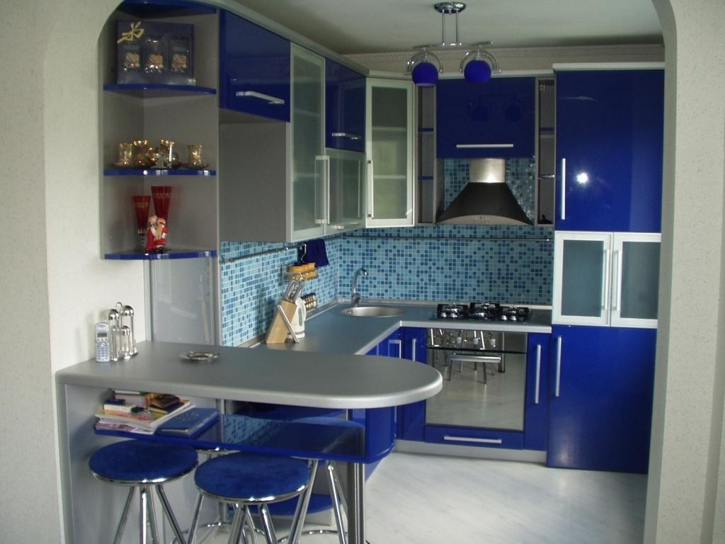 The kitchen looks stylish, where the dark blue facades of the cabinets coexist with the snow-white walls, a counter and an apron.