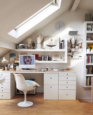 A small office is separated from the rest of the room by a shelf or a light cabinet.