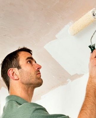 The ceiling is painted with a spray gun or a long-handled roller.